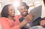 Couple sitting on sofa looking at digital tablet