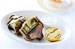 Grilled artichokes with lemon on restaurant table