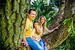 Portrait of mature couple and daughter sitting on garden tree branch