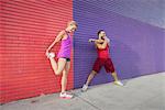 Male and female runners warming up on sidewalk