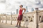 Male runner leaning back taking a break on bridge, Los Angeles, California, USA