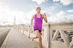 Young female runner running across bridge, Los Angeles, California, USA