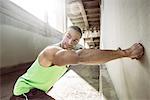 Muscular male runner doing wall push ups under city bridge