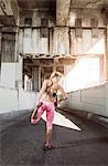 Rear view of female runner warming up under city bridge