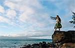 Woman hula dancing on top of coastal rocks wearing traditional costume, Maui, Hawaii, USA