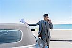 Young businessman at coastal parking lot talking on smartphone