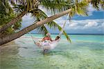 Senior man relaxing in hammock with woman, Maldives