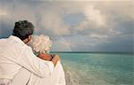 Senior couple looking at rainbow over sea, Maldives