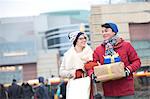 Happy couple with gifts and shopping bags walking in city during winter