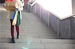 Low angle view of woman with gifts and shopping bags moving down steps