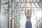 Confident woman exercising with gymnastic rings in crossfit gym