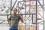 Confident man doing chin-ups in crossfit gym