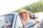 Female friends sitting in convertible on sunny day