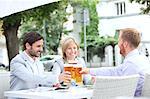 Happy businesspeople toasting beer glasses at outdoor restaurant