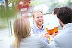 Happy businessman toasting beer glass with colleagues at outdoor restaurant