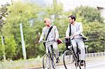 Businessmen talking while cycling outdoors