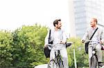 Businessmen talking while riding bicycles outdoors