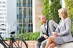 Happy businessman talking to female colleague in city