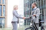 Happy businesspeople shaking hands outside office building