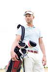 Low angle view of thoughtful mid-adult man carrying golf club bag against clear sky