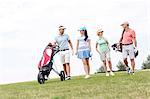 Friends talking while walking at golf course against clear sky