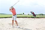 Man swinging at golf course against sky