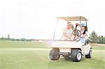 Couple looking at each other while sitting in golf cart against clear sky