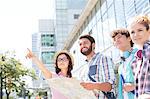 Happy friends with road map with woman pointing away in city