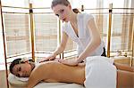 Portrait of young woman receiving massage from masseuse