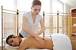 Portrait of young woman receiving massage from masseuse