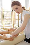 Young woman receiving foot massage from masseuse