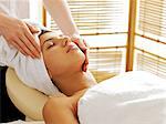 Young woman receiving facial massage, eyes closed