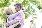 Side view of middle-aged couple embracing while looking at each other in park