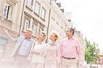 Middle-aged man showing something to friends while walking in city