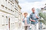 Happy middle-aged couple holding ice cream cones while walking in city