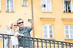 Happy middle-aged couple taking selfie through camera against building