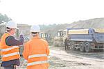 Supervisor explaining plan to colleague at construction site