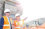 Supervisor showing something to colleague at construction site on sunny day