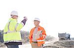 Supervisors discussing at construction site against clear sky