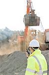 Side view of engineer using walkie-talkie at construction site