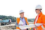 Engineers discussing at construction site against clear sky