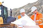 Engineers analyzing blueprint at construction site