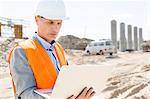 Supervisor using laptop at construction site on sunny day