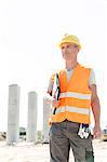 Thoughtful architect looking away while holding clipboard at construction site