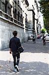 Teenager walking along the street carrying a bag