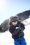 A 3 years old little boy playing with snow in the mountains, in winter