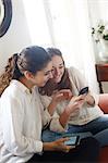 2 teens playing with their mobile phone on a sofa