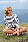 France, smiling French redhead girl sitting in a mountain meadow, teenager.