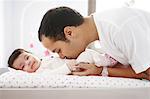 A 2 months old baby girl on a changing table, her dad taking care of her
