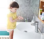 Little girl washing hands in a bathroom sink